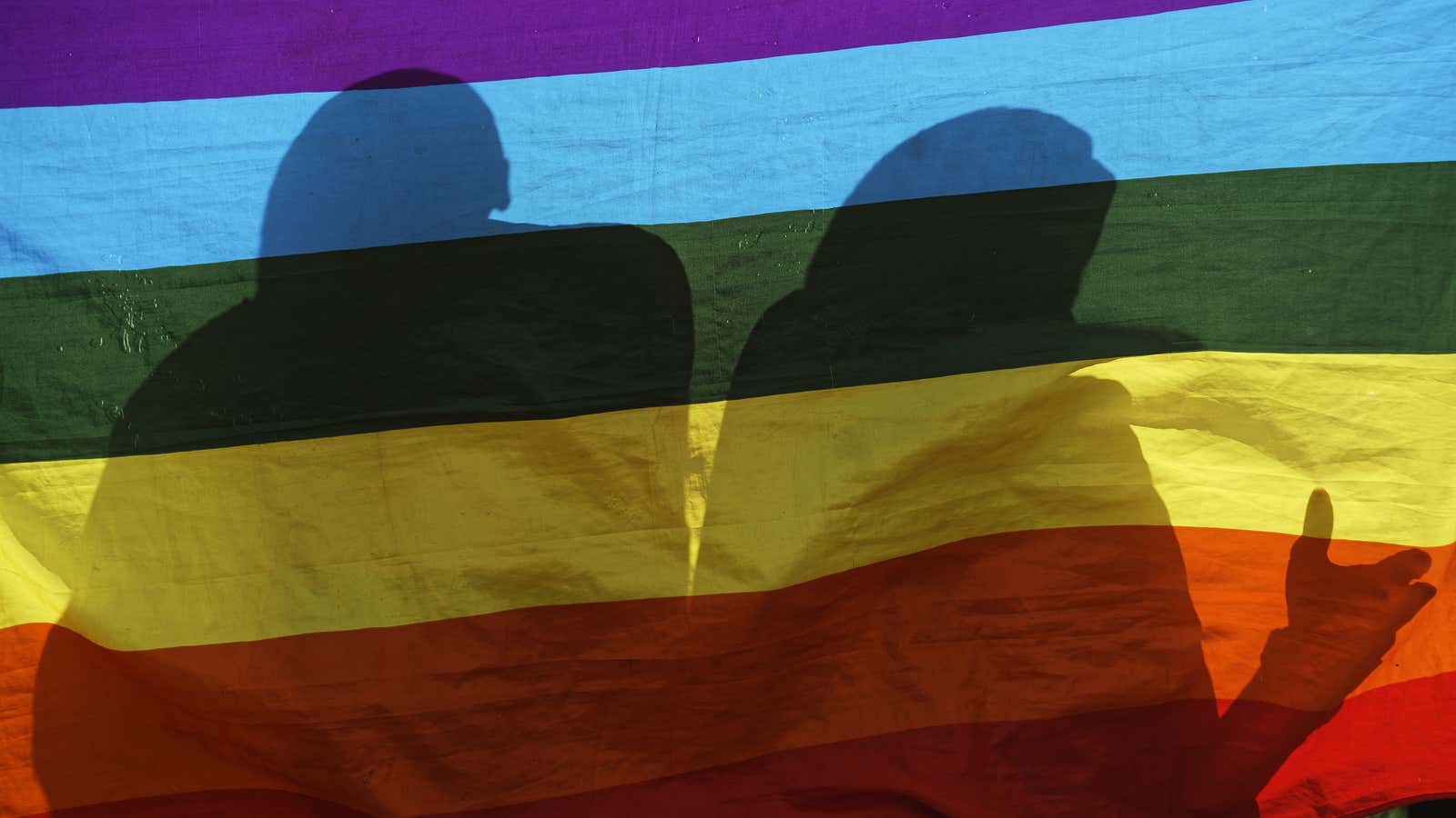 LGBTQ refugees in Kenya stand behind a Pride flag.