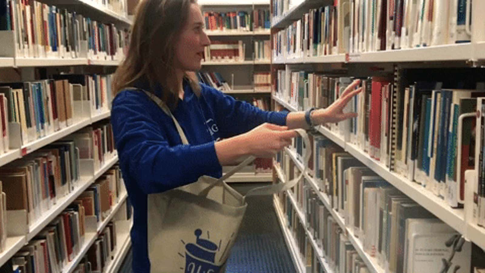 A woman stuffs books into her tote bag