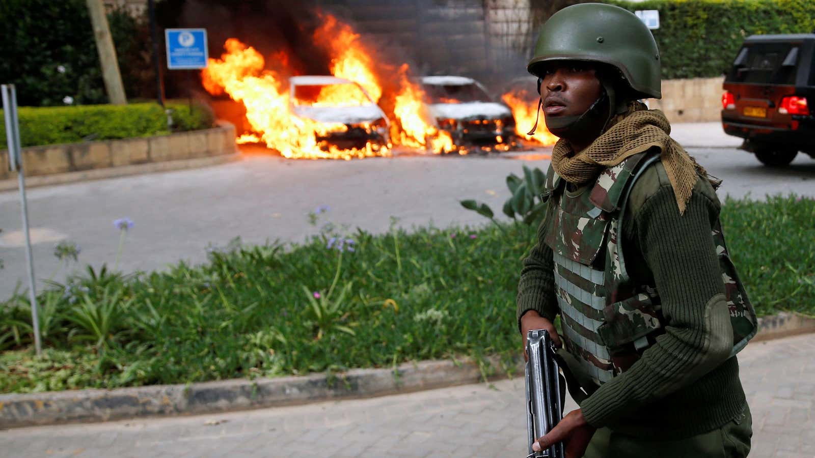 A policeman runs past burning cars at the scene where explosions and gunshots were heard at the Dusit hotel compound, in Nairobi, Kenya Jan. 15, 2019.