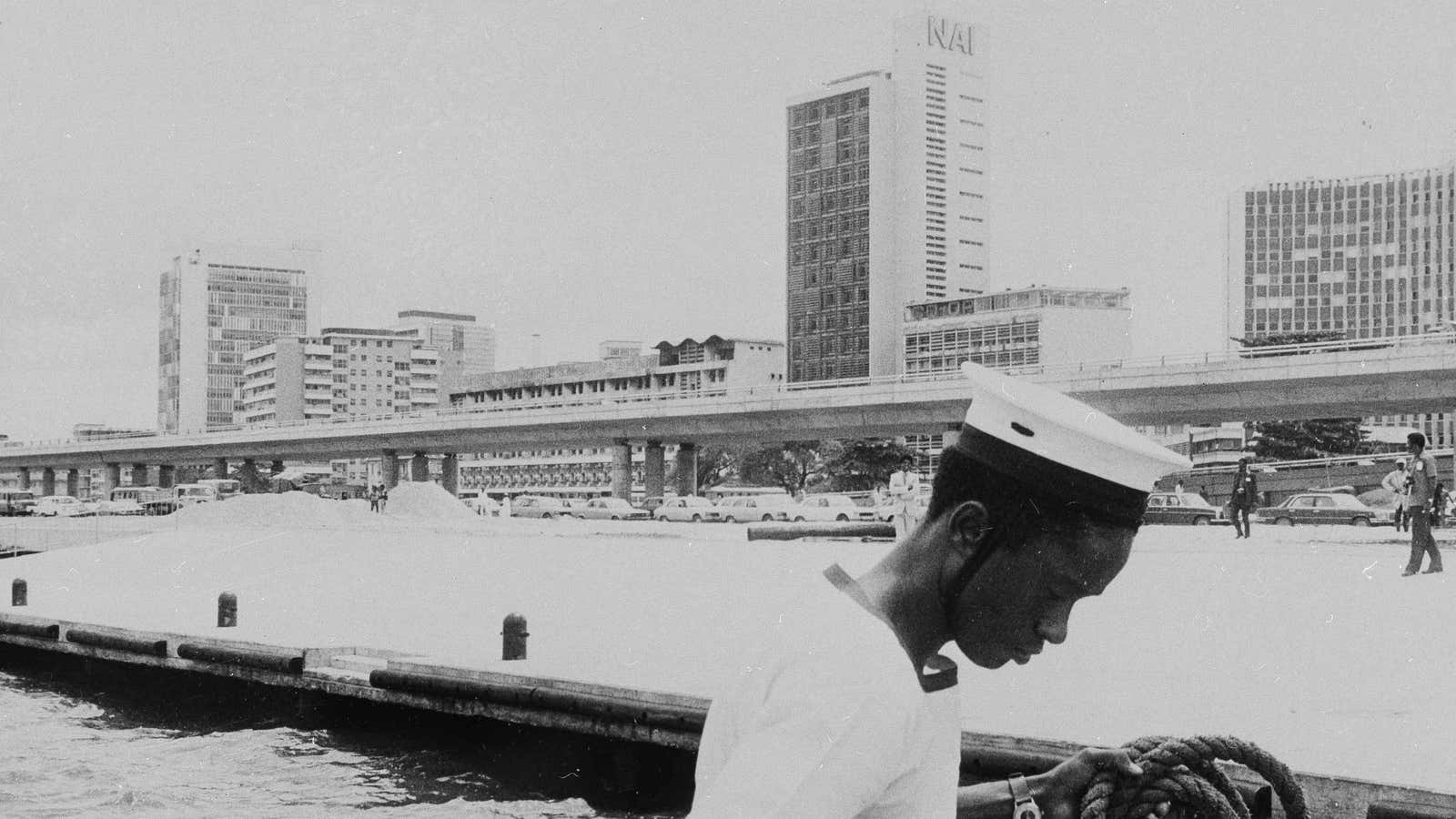 A Nigerian Navy man is silhouetted against the 1978 skyline of downtown Lagos