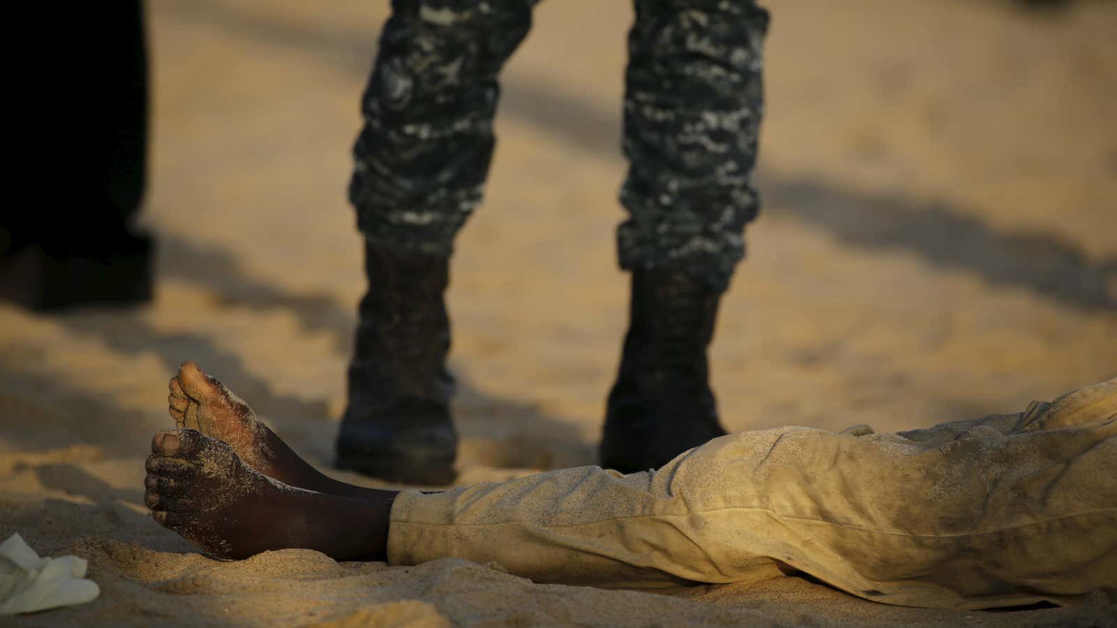A soldier stands over a person killed on a beach after an attack in Grand Bassam, Ivory Coast.