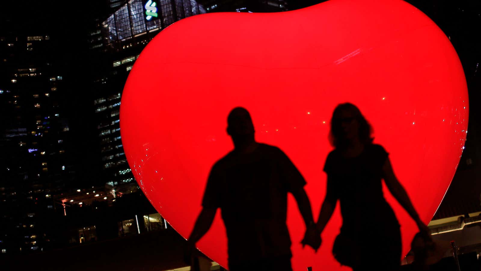 A couple is silhouetted against an inflatable heart by french artist Franck Pelletier, in the financial district of Singapore on Wednesday, March 7, 2018, in…