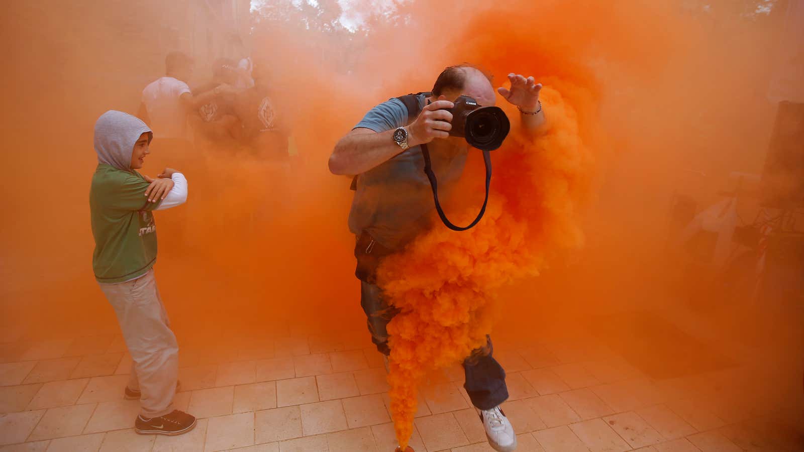 A photographer jumps over a smoke canister during a demonstration.