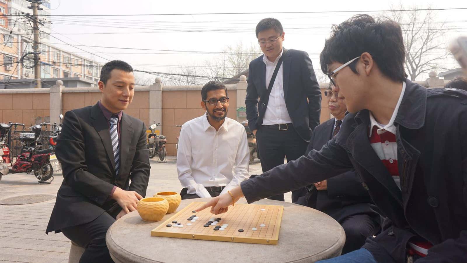 Ke Jie, right, talks with Google CEO Sundar Pichai, center, about an AlphaGo game.