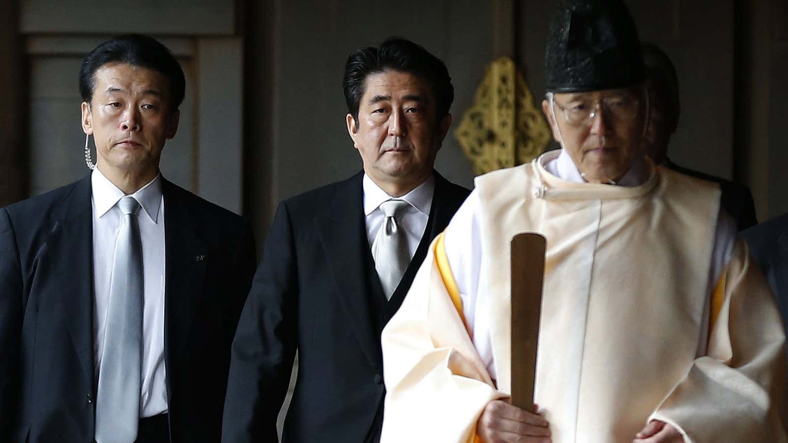 Japan’s Prime Minister Shinzo Abe is led by a Shinto priest as he visits Yasukuni shrine in Tokyo