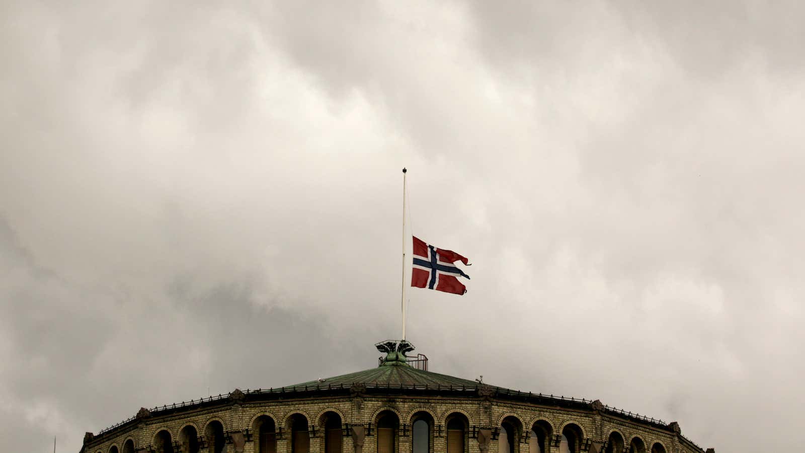The Norwegian flag flutters at half-mast on the roof of the parliament building in Oslo July 23, 2011. Norwegian police searched for more victims on…