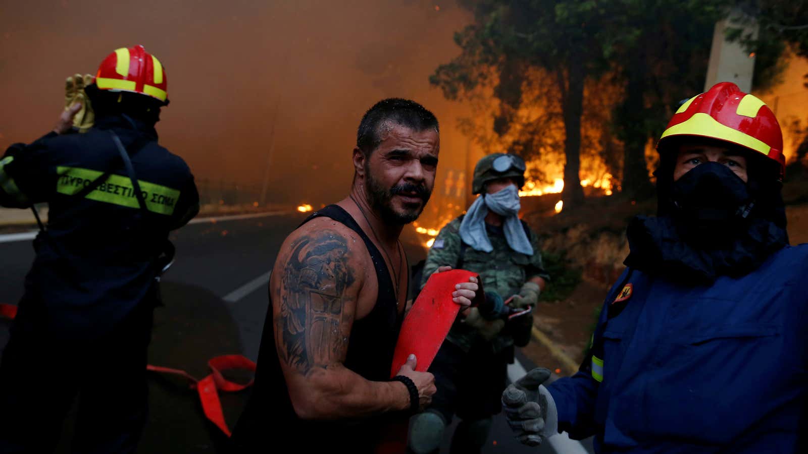Firefighters, soldiers and local residents carry a hose in the town of Rafina near Athens.