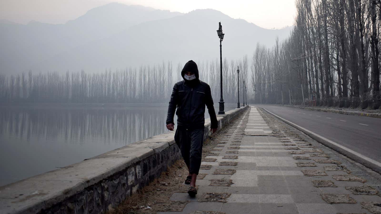 A man wearing a protective face mask walks along the banks of Dal Lake on a cold morning in Srinagar December 23, 2020.
