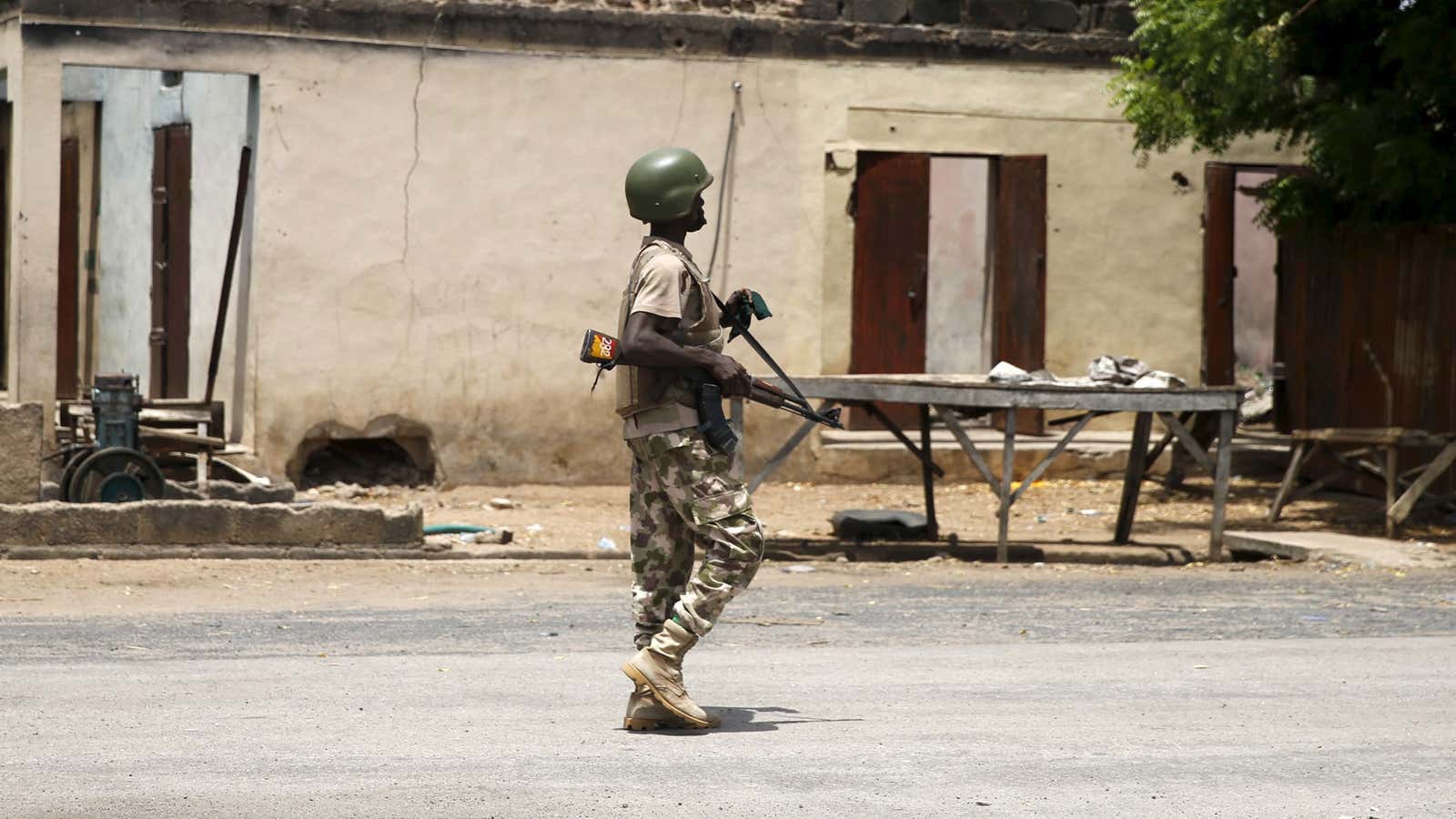 A soldier walks past a burnt building in Michika town, a town which was once occupied by Boko Haram