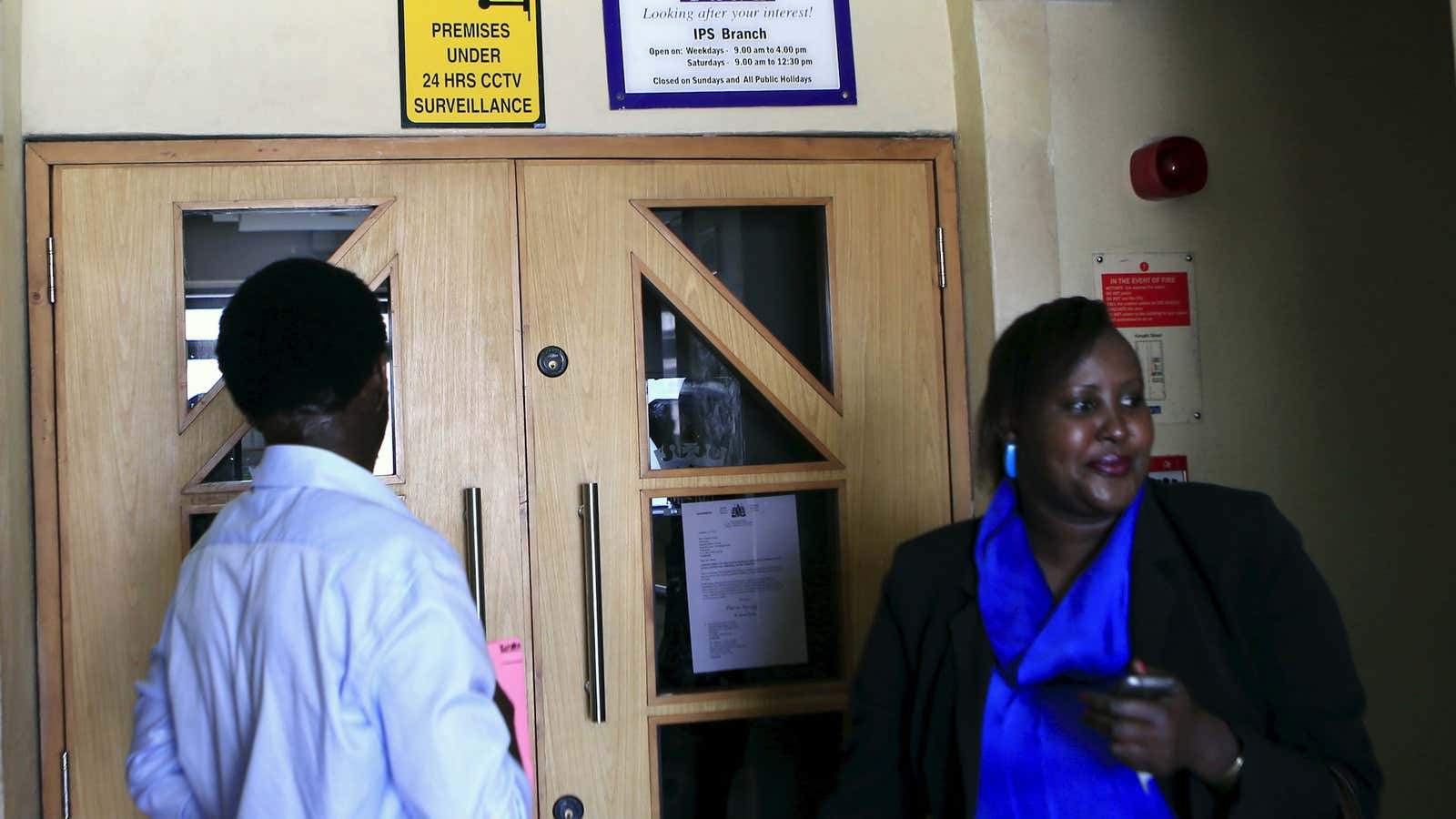 Customers of Imperial Bank wait outside a shuttered branch in Nairobi.