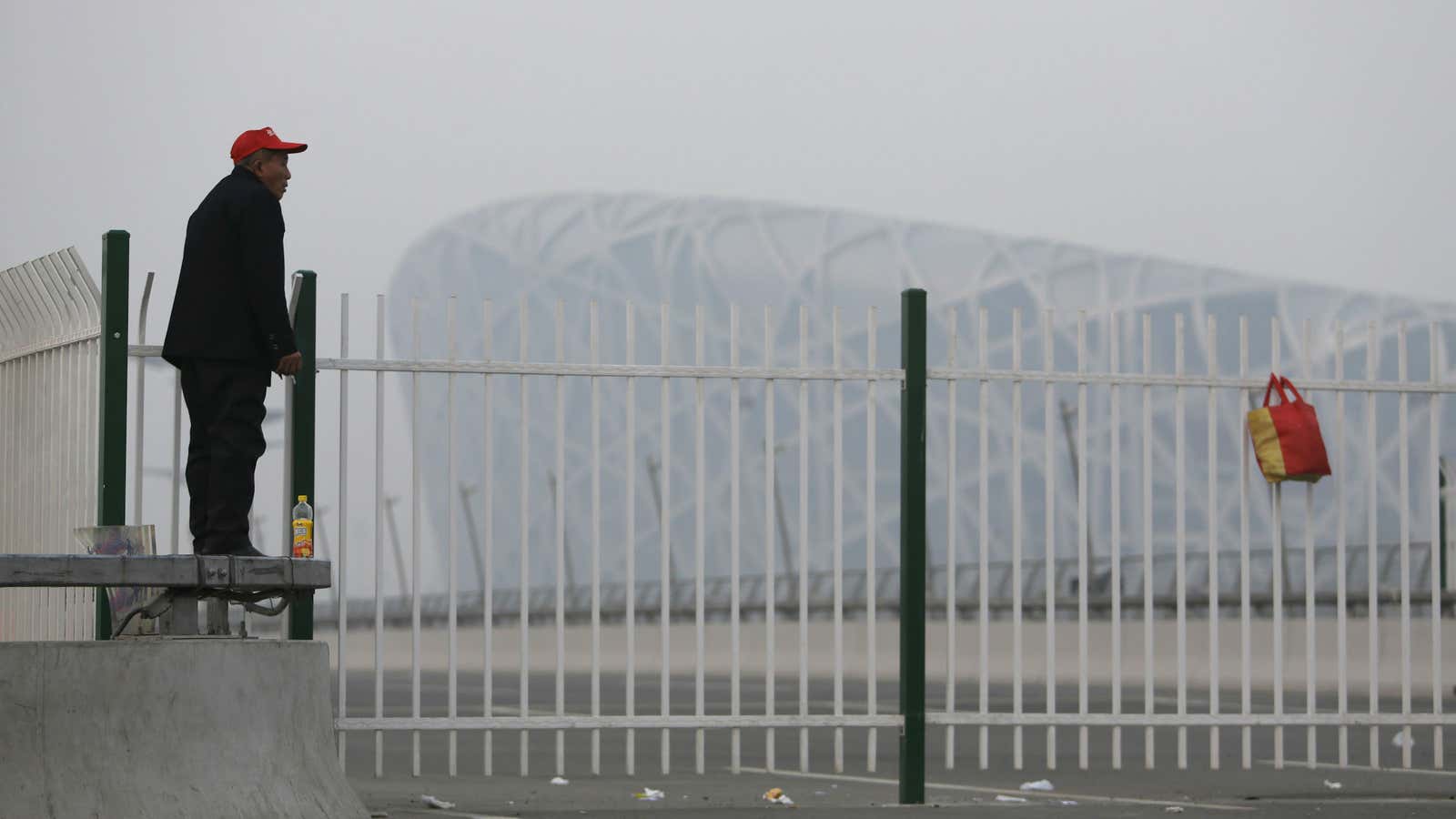 A tourist stands near the National Stadium, also known as the Bird’s Nest, on a smoggy day in Beijing.