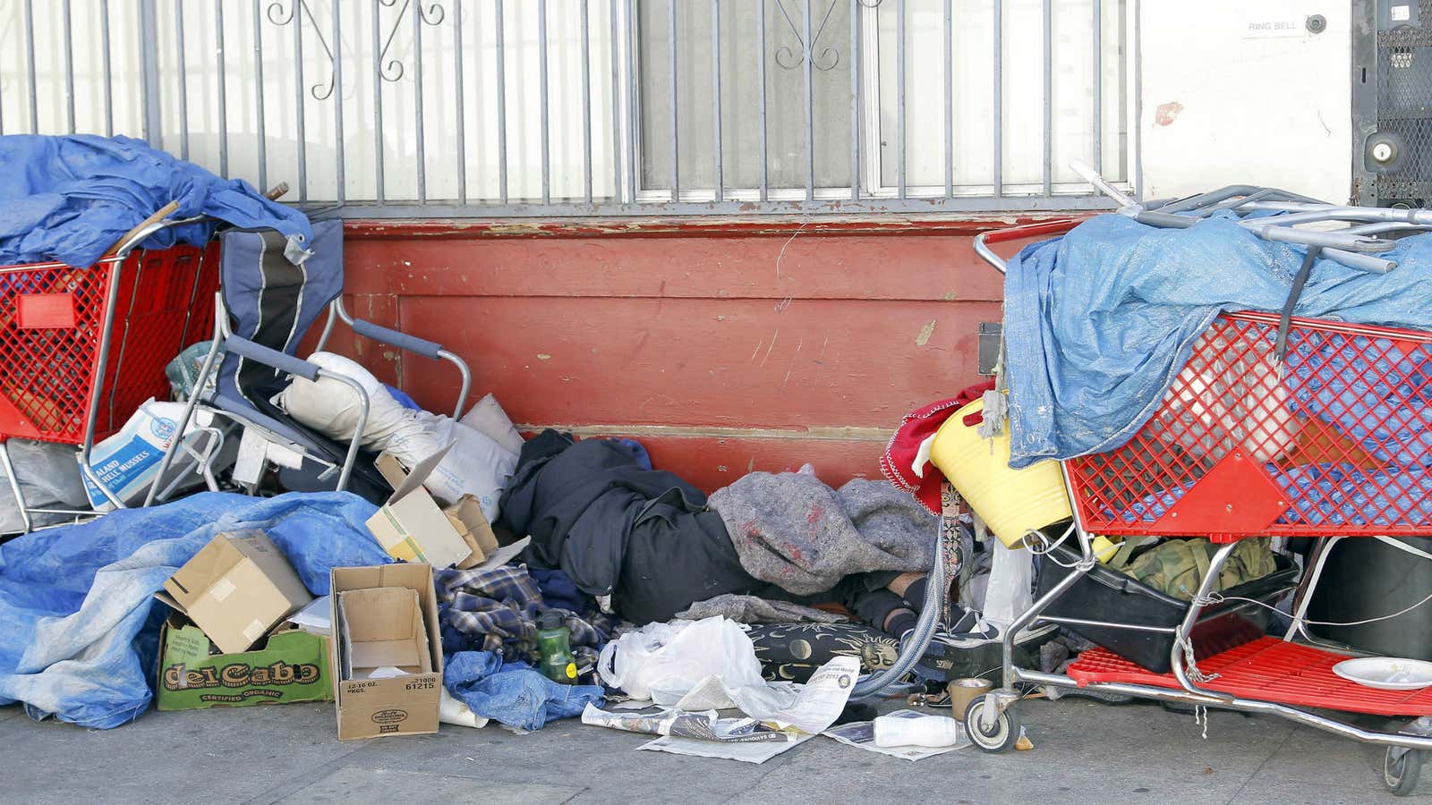 A homeless man sleeps among his possessions on Skid Row.