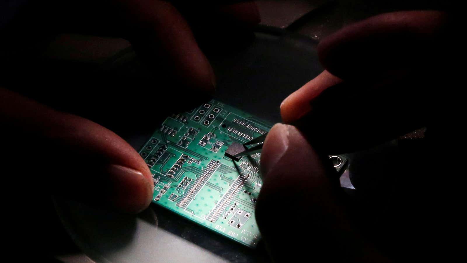 FILE PHOTO: A researcher plants a semiconductor on an interface board which is placed under a microscope during a research work to design and develop…