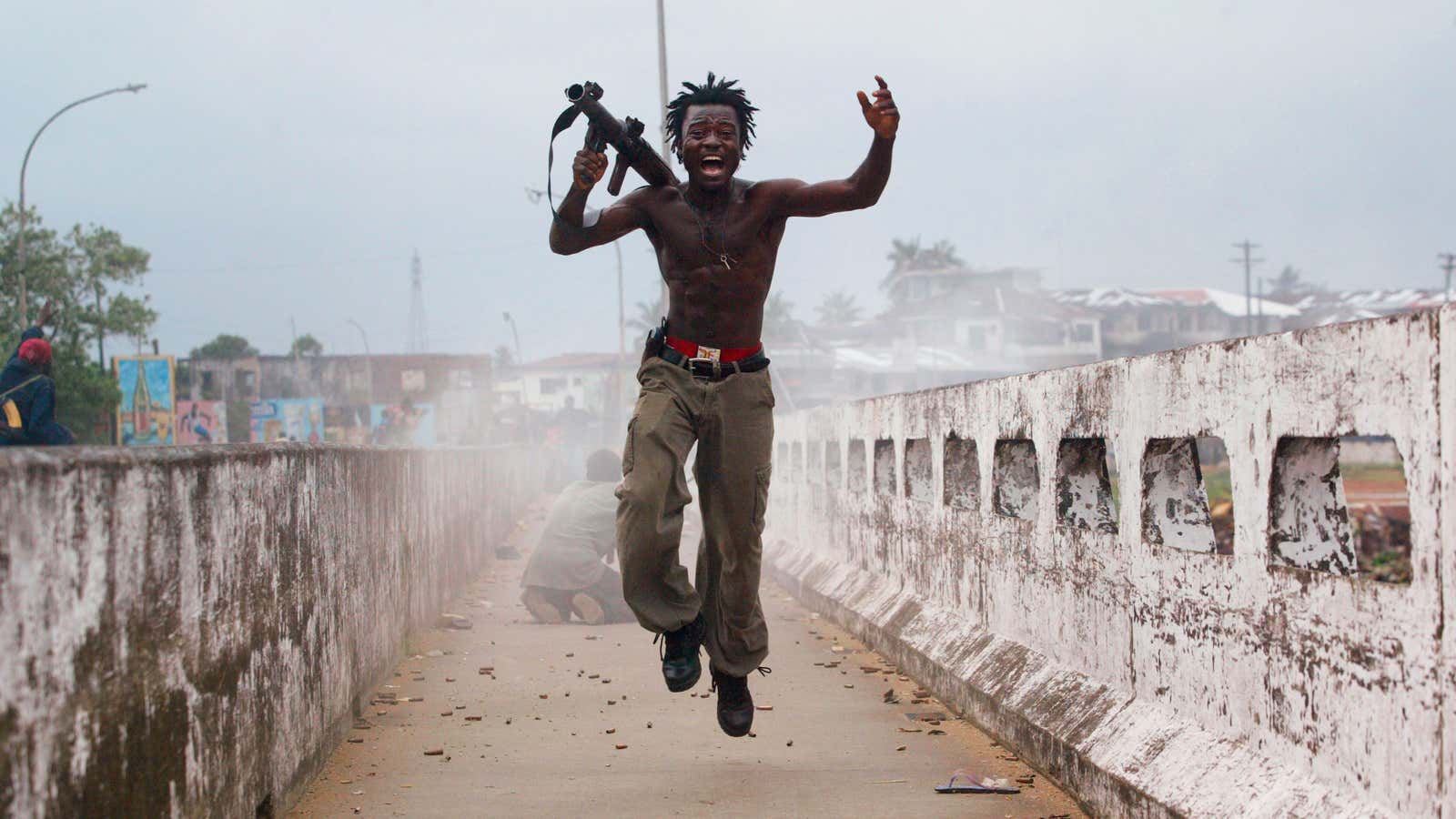 Joseph Duo, a Liberian militia commander loyal to the government, exults after firing a rocket-propelled grenade at rebel forces at a key strategic bridge