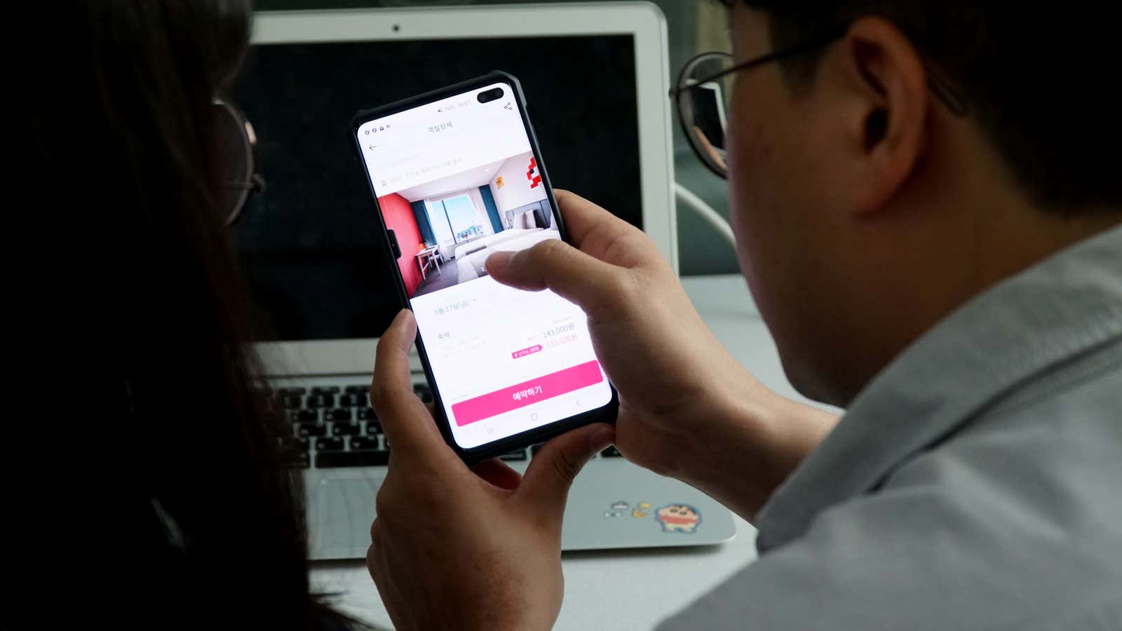 A couple looks at South Korea’s accommodation-booking app on a mobile phone during a photo opportunity in Seoul, South Korea, May 17, 2019. Picture taken…