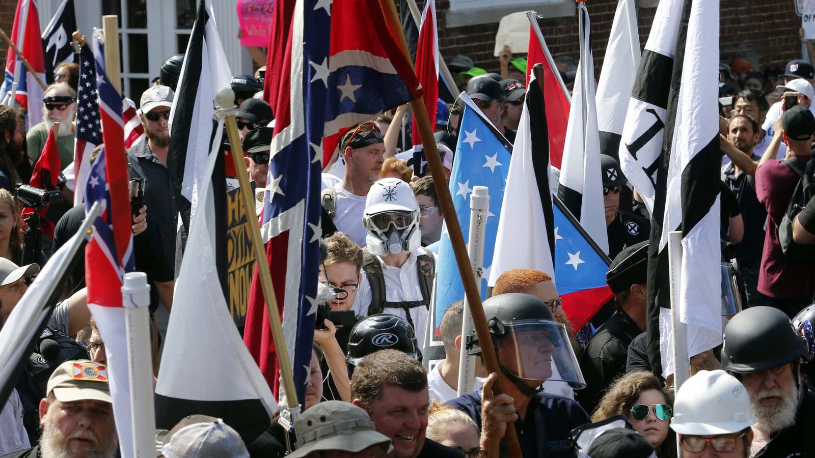 FILE – In this Saturday, Aug. 12, 2017, file photo, white nationalist demonstrators walk into the entrance of Lee Park surrounded by counter demonstrators in…