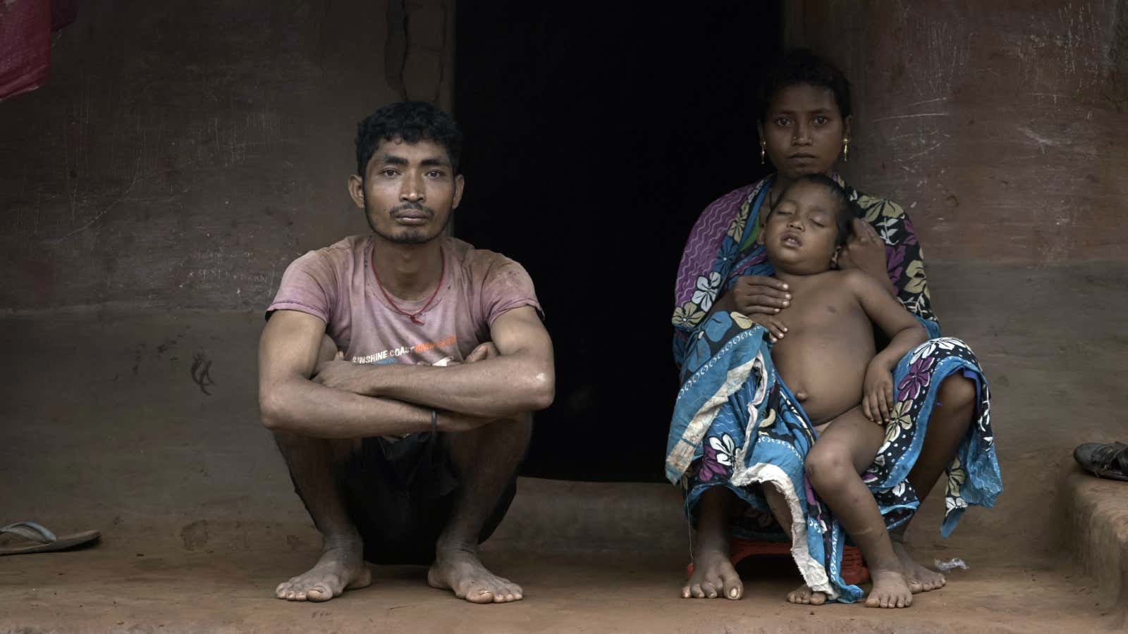 Deso and Basanti Padhan sit on their porch, holding their four-year-old son, Kushan.