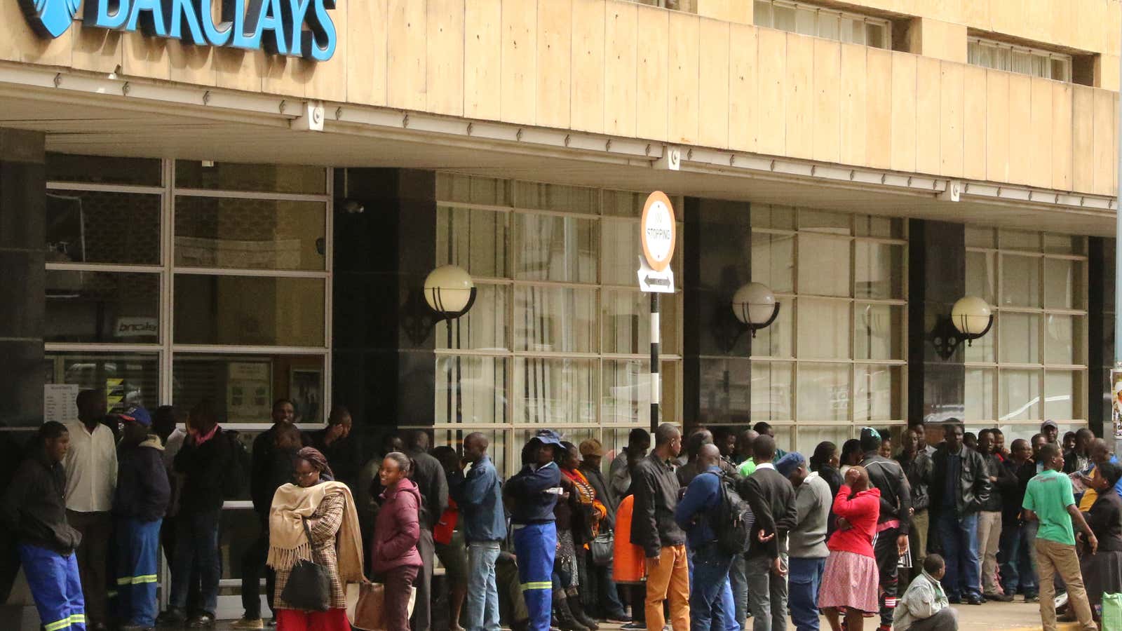 People queue to withdraw cash from a branch of Barclays bank in Harare.