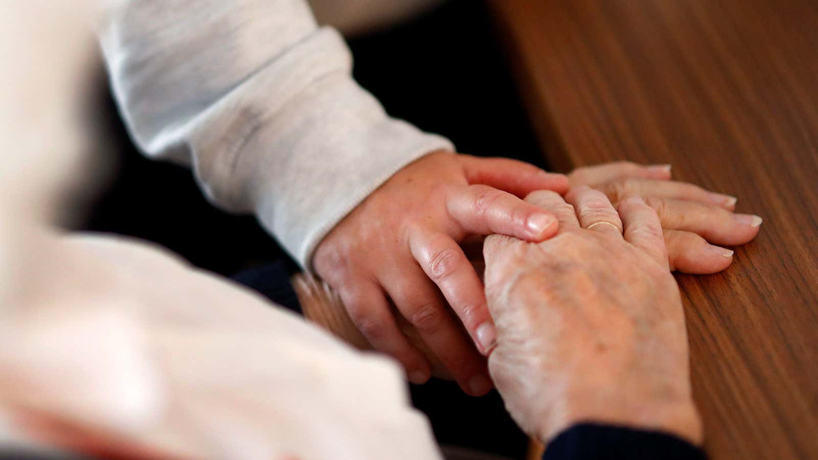 A hand holds that of of an unseen elderly person