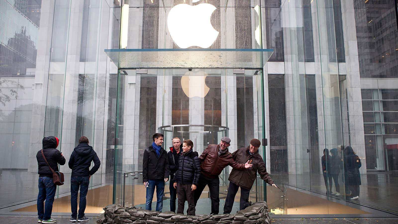 People pose outside the sandbagged entrance of the Apple Store on Fifth Avenue in New York