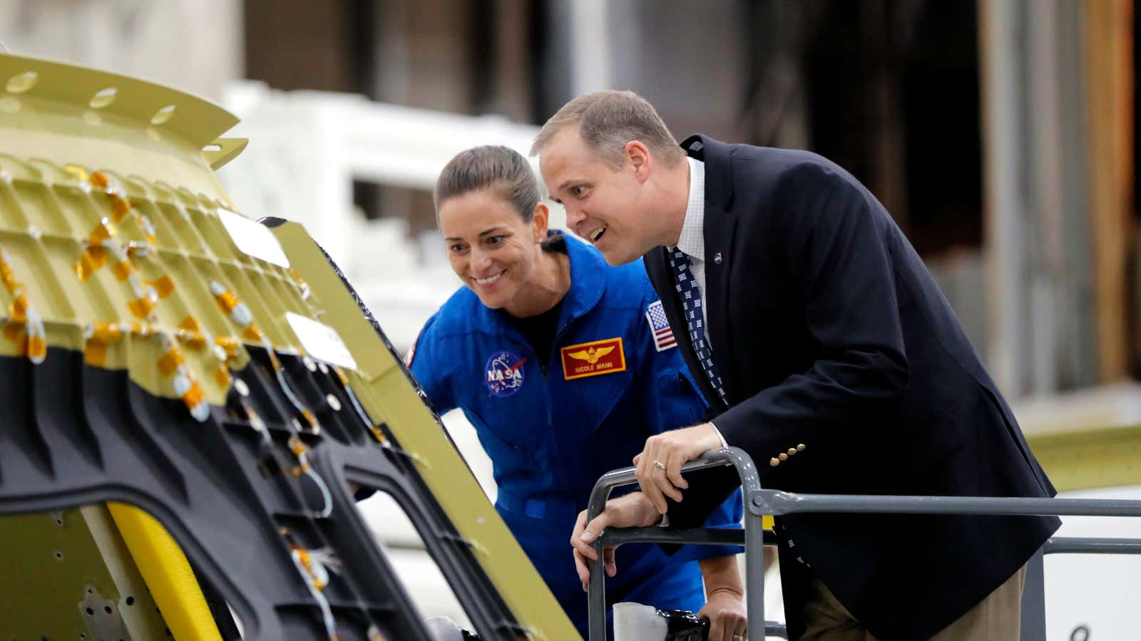 NASA administrator James Bridenstine and astronaut Nicole Mann examine a spacecraft under construction.