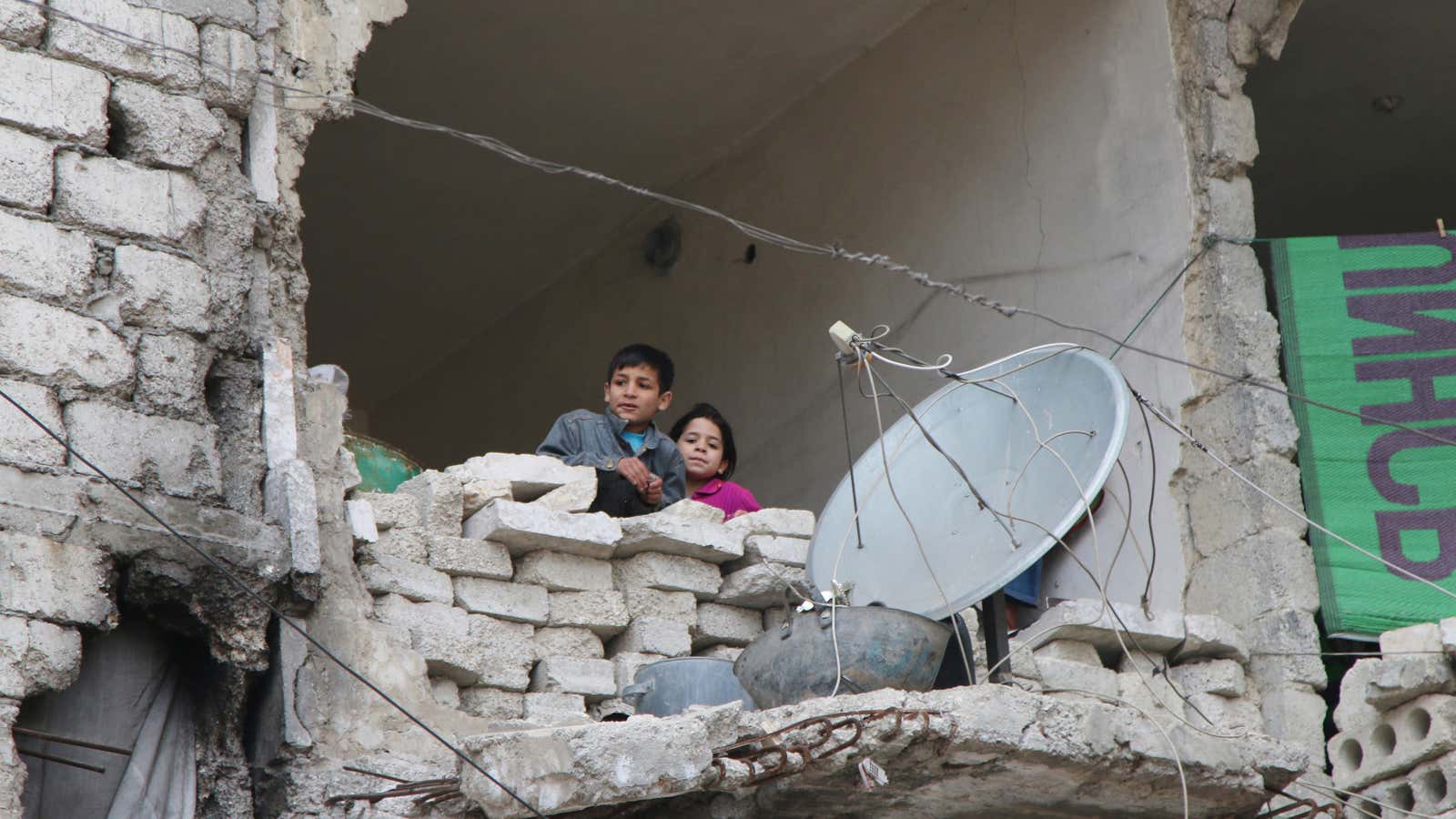 Children peer from a partially destroyed home in Aleppo, Syria.