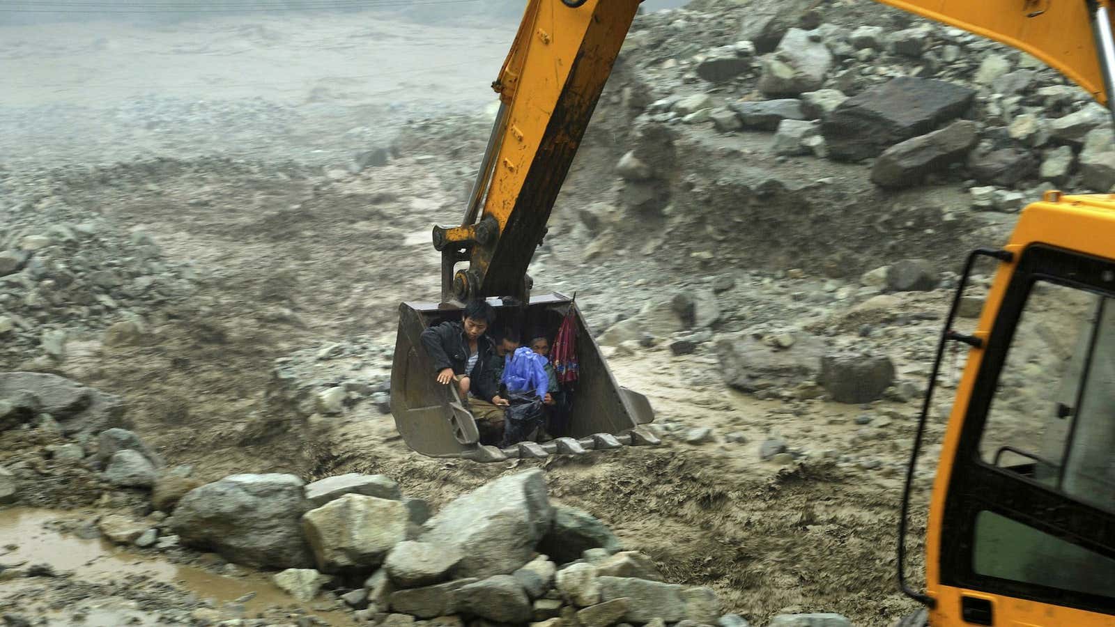 An excavator moves villagers away from a flooded area in Sichuan province in July, 2013.