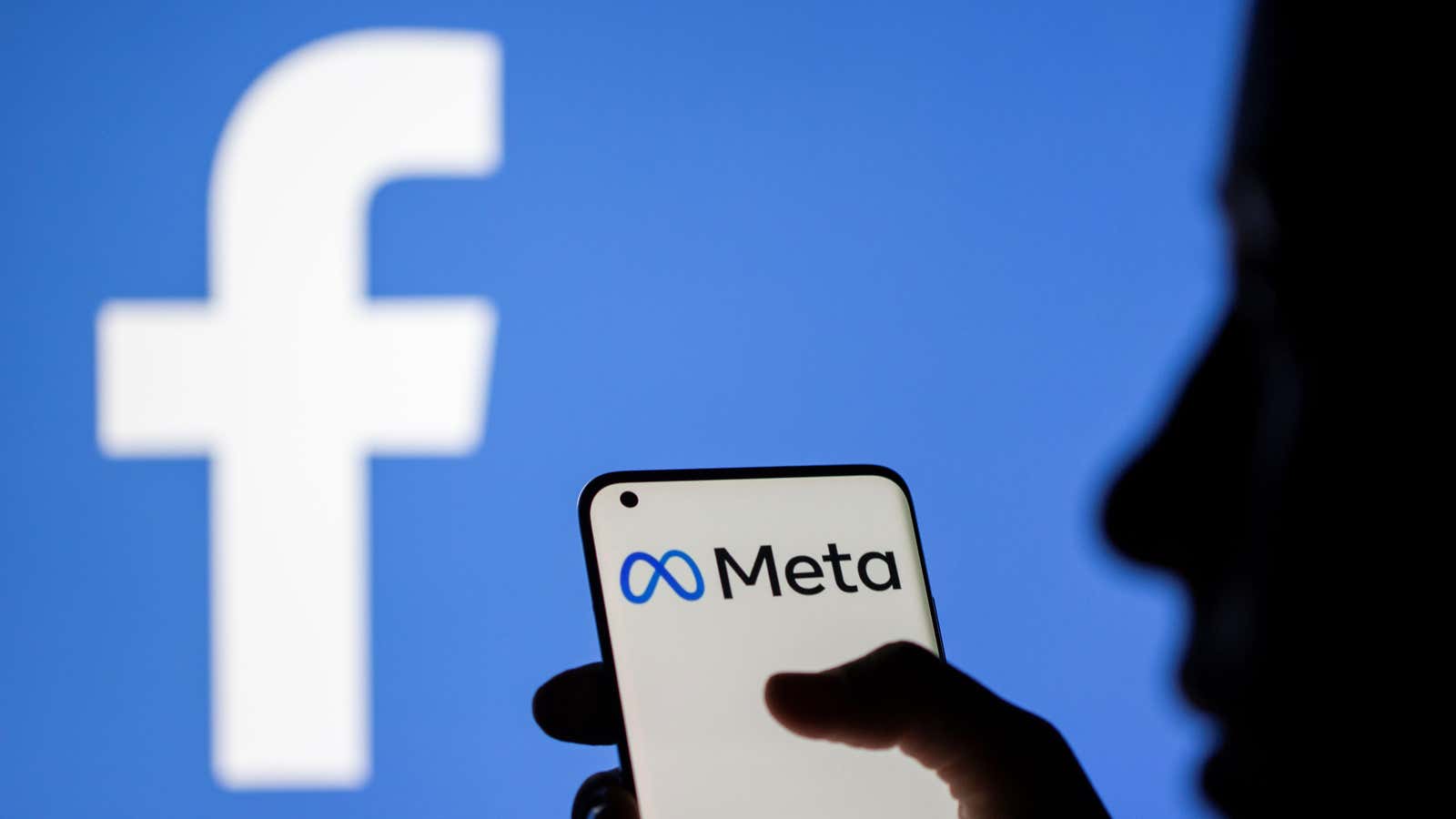 The Meta logo with Facebook’s old branding in the background