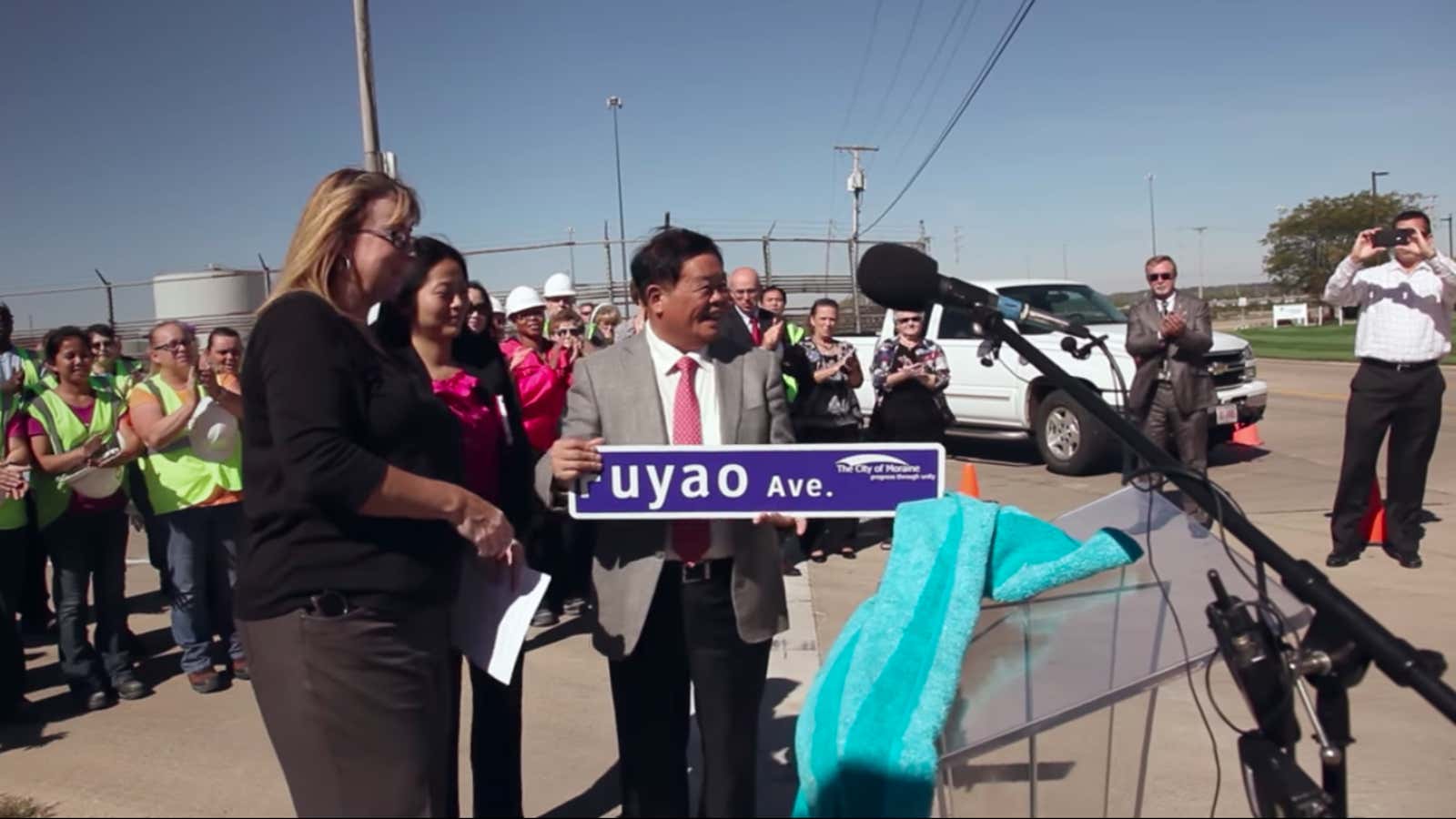 Cao Dewang, founder of Fuyao, accepts an Ohio street sign named after the company.