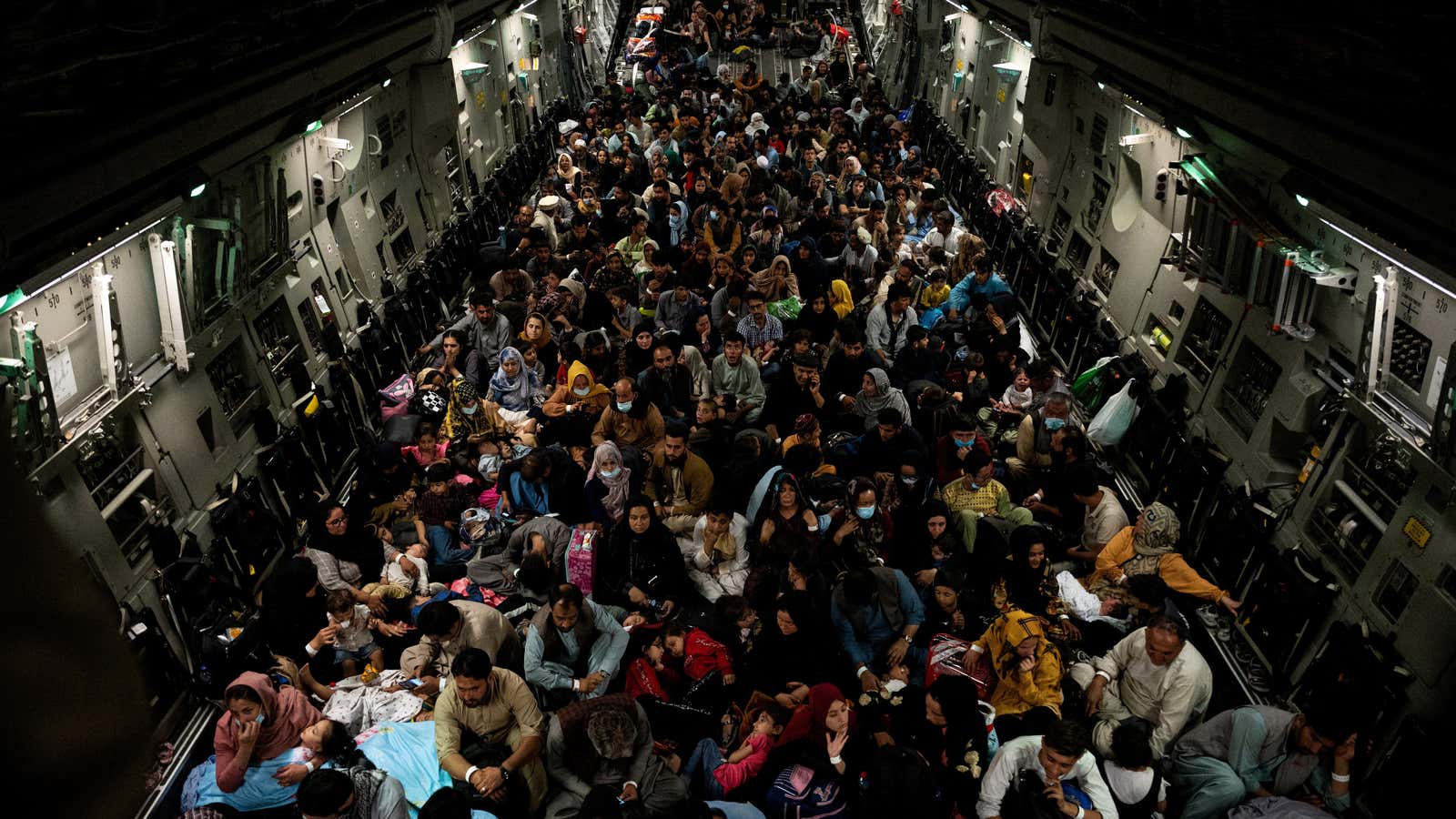 Evacuees from Afghanistan sit inside a military aircraft.