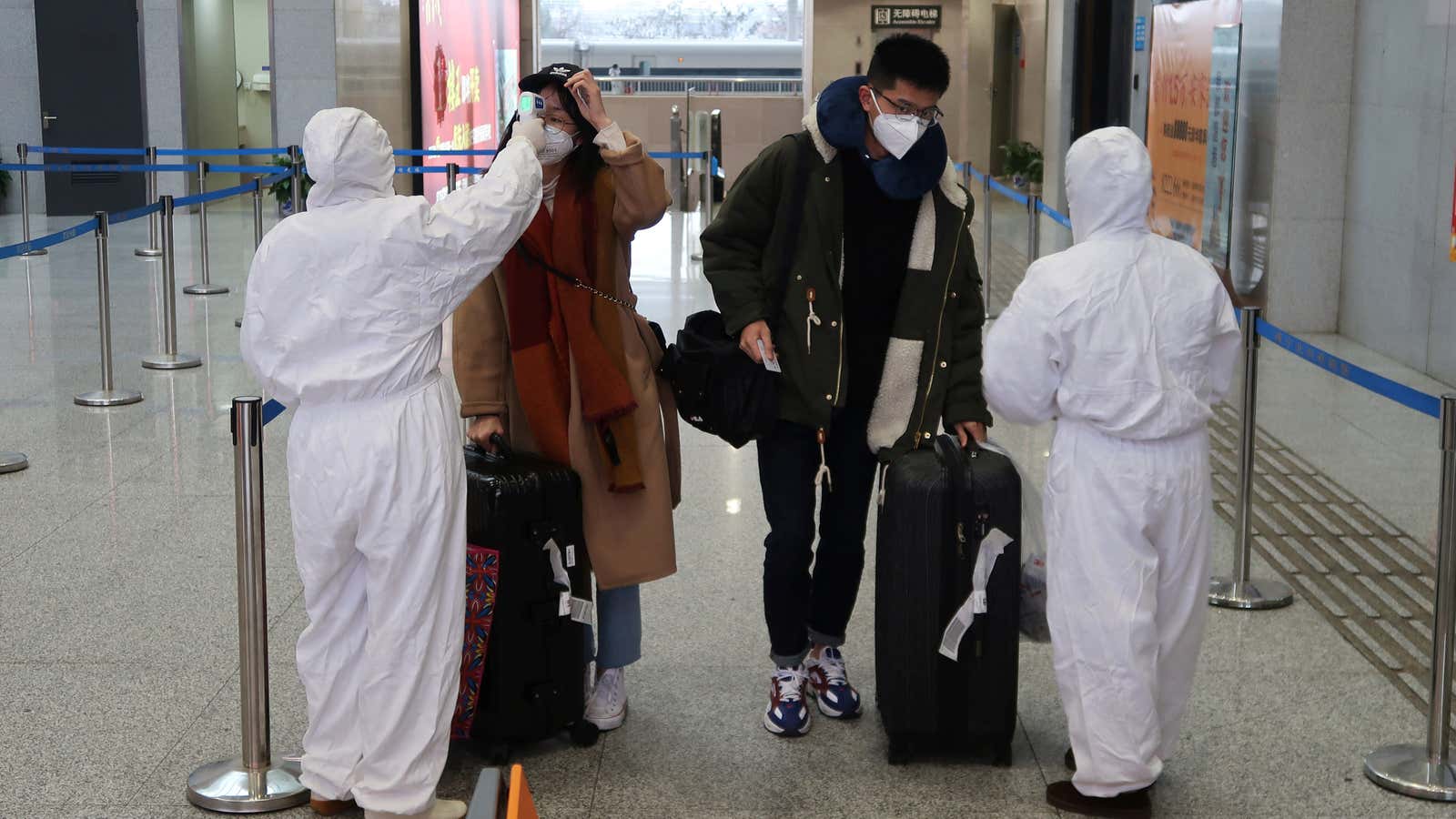 Workers in protective suits check the temperature of passengers arriving at a station in Xianning, a city bordering Wuhan in Hubei province, China Jan. 24, 2020.