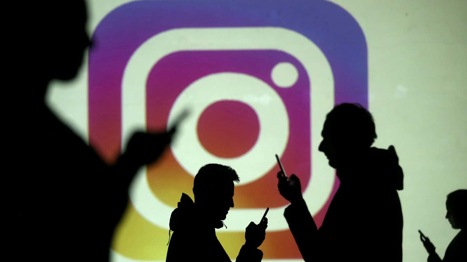 FILE PHOTO: Silhouettes of mobile users are seen next to a screen projection of the Instagram logo in this picture illustration taken March 28, 2018.…