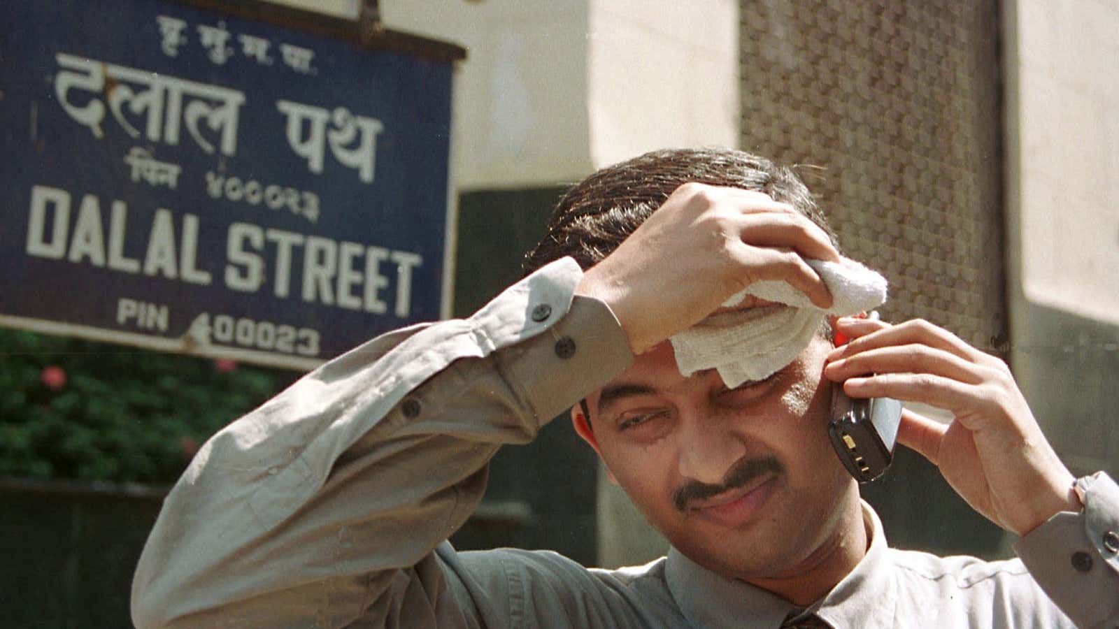 A stockbroker wipes his brow while he speaks on the phone outside the Bombay Stock Exchange, April 11, 2001. Technology stocks pulled Indian shares nearly…