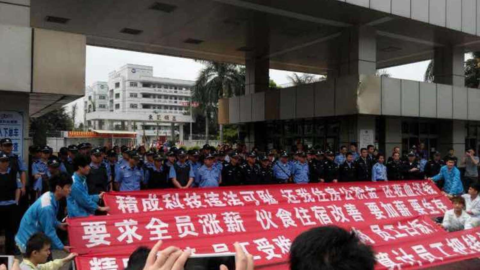 Workers at Yue Yuen, wearing the blue uniforms of the factory, on strike on March 20. “Yue Yuen is breaking the law,” their sign reads. “We are fighting for justice.”