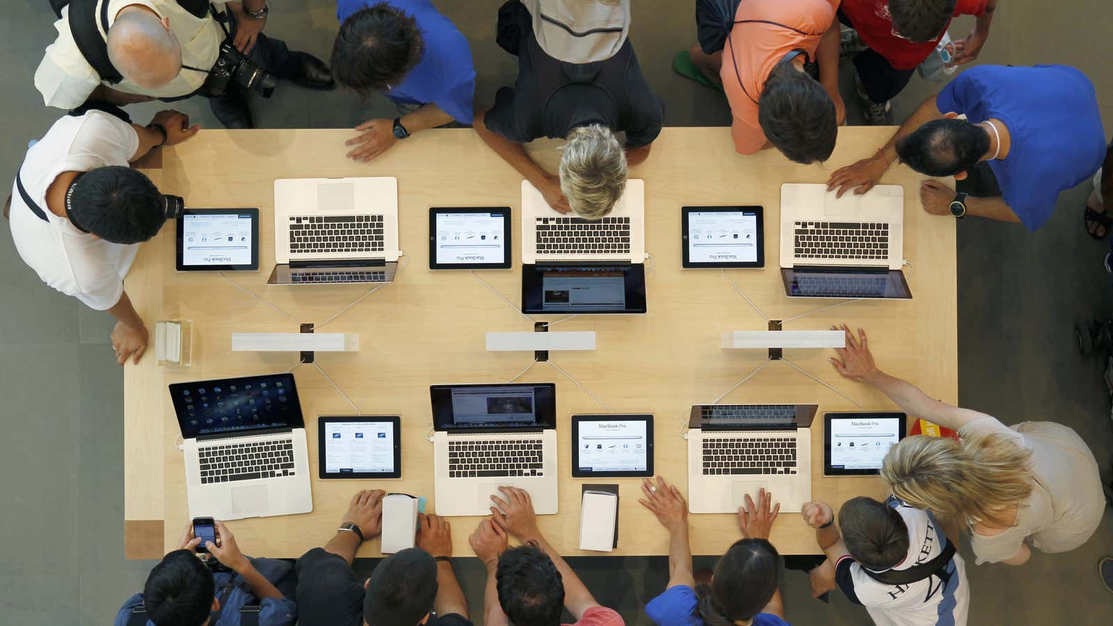Employees and customers surround a table with MacBook Pros, during the official opening of the largest Apple shop in southern Europe, at Passeig de Gracia…