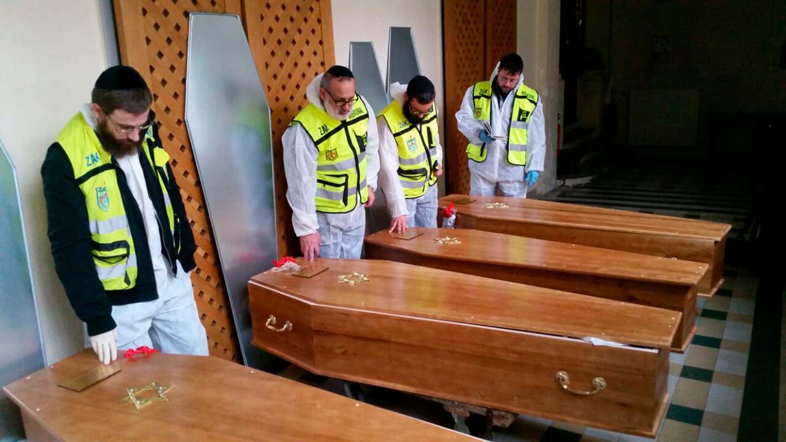 Members of the Zaka emergency response team pray beside the coffins of four victims of an attack at a kosher supermarket in Paris.