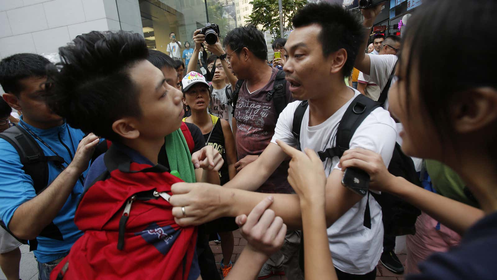A pro-democracy student protester gets pressed by angry counter-demonstrators.