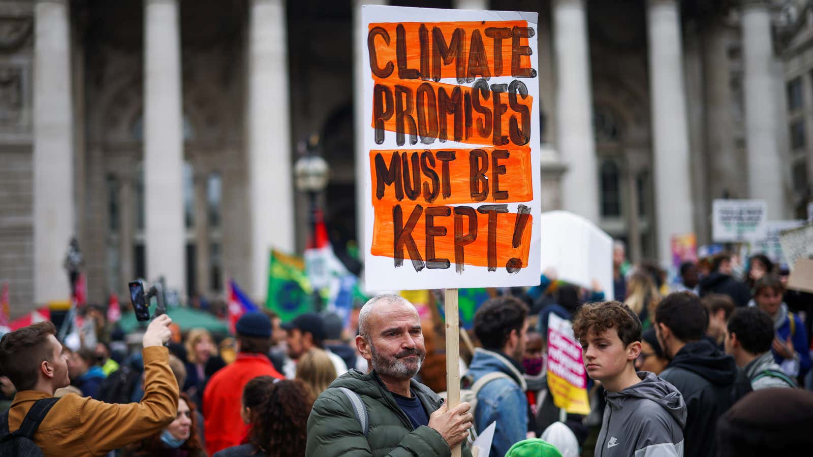 A man holds a sign that says, Climate promises must be kept! at a climate protest in London.