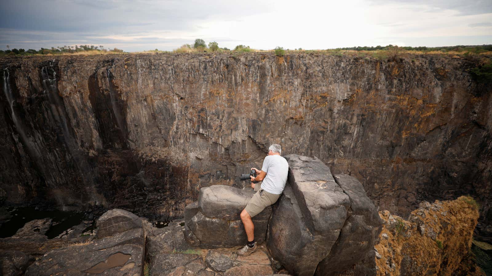 Visitors take pictures before dry cliffs following a prolonged drought at Victoria Falls, Zimbabwe, Dec. 4, 2019.