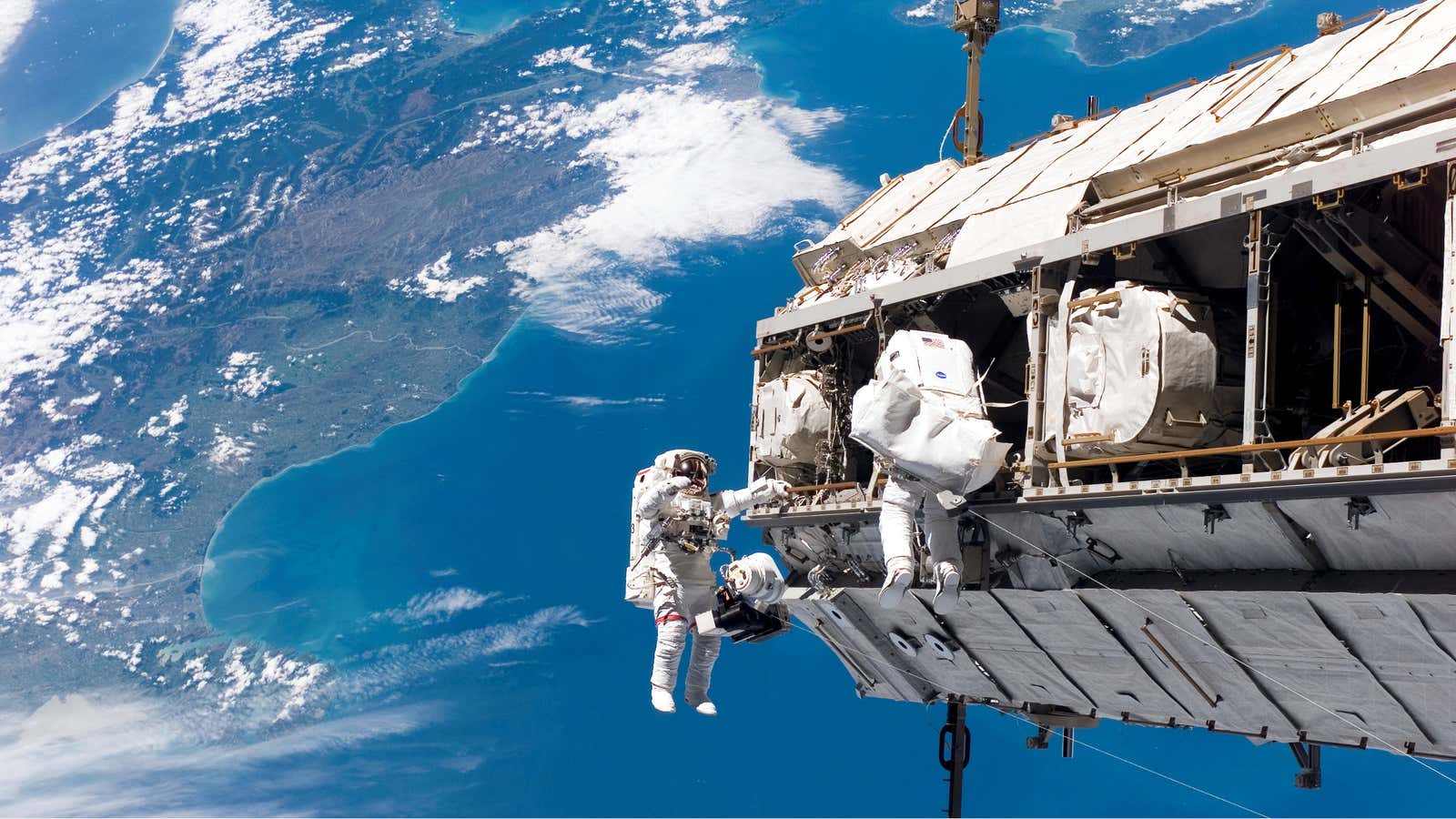 Two astronauts construct the International Space Station over New Zealand in 2006.