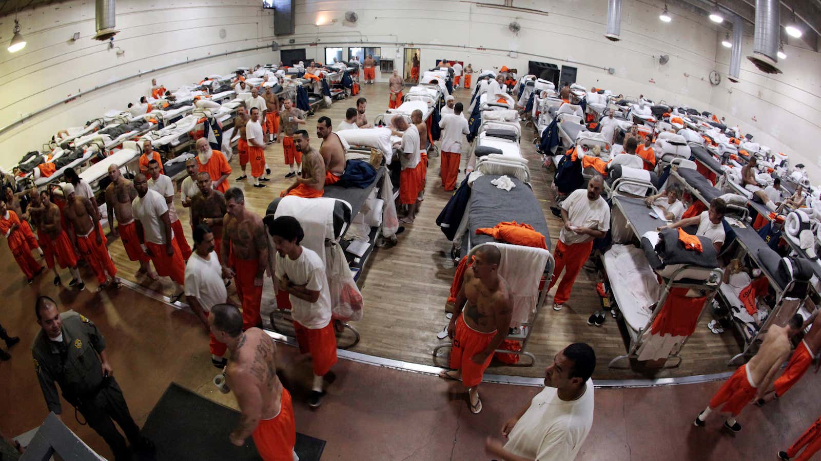 Inmates walk around a gymnasium where they are housed due to overcrowding at the California Institution for Men state prison in Chino, California, June 3,…