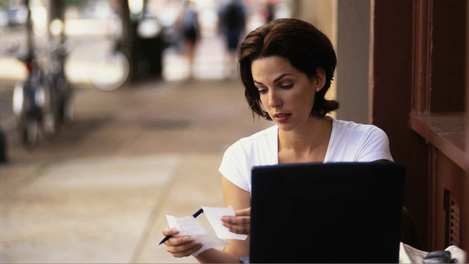 Businesswoman working at sidewalk cafe with laptop