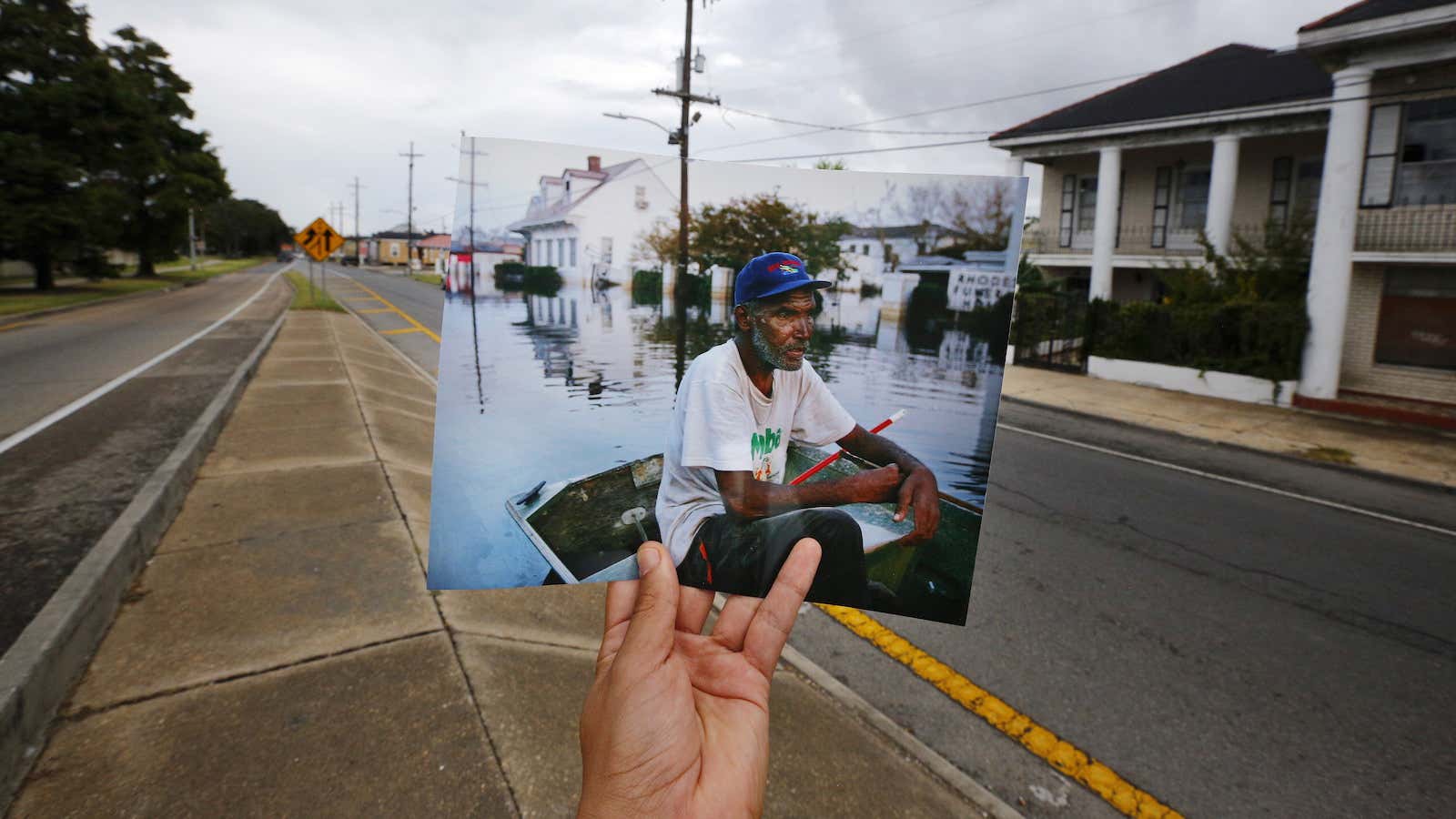 Photographer Carlos Barria holds a print of a photograph he took in 2005, as he matches it up at the same location 10 years on, in New Orleans.