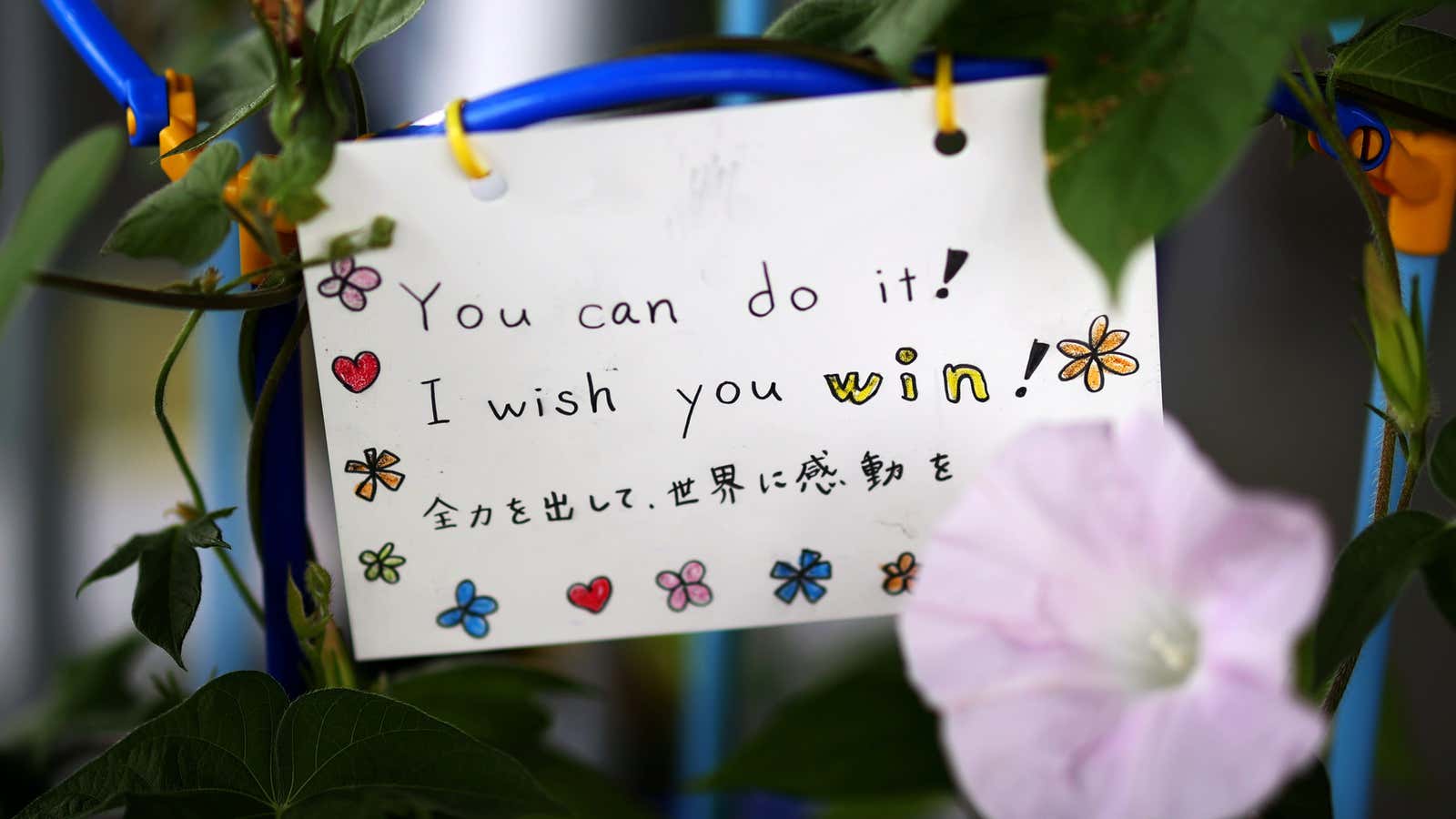 A message left on a plant of flowers is pictured outside the Ariake Tennis Park at the Tokyo 2020 Olympic Games in Tokyo, Japan, July 26, 2021. REUTERS/Mike Segar
