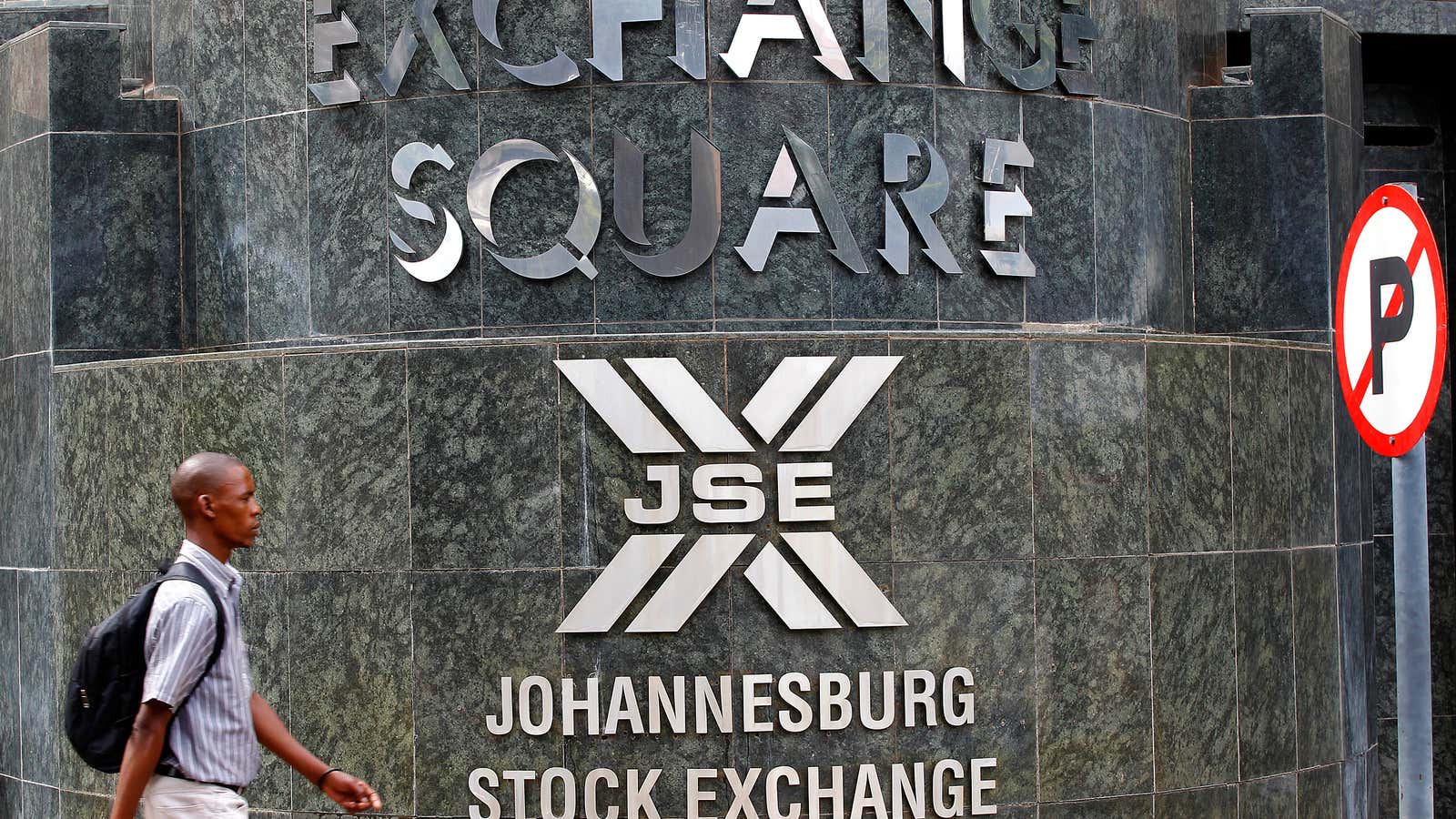 A man walks past the Johannesburg Stock Exchange building in Sandton December 6, 2012. South Africa’s black majority directly owns less than 10 percent of…