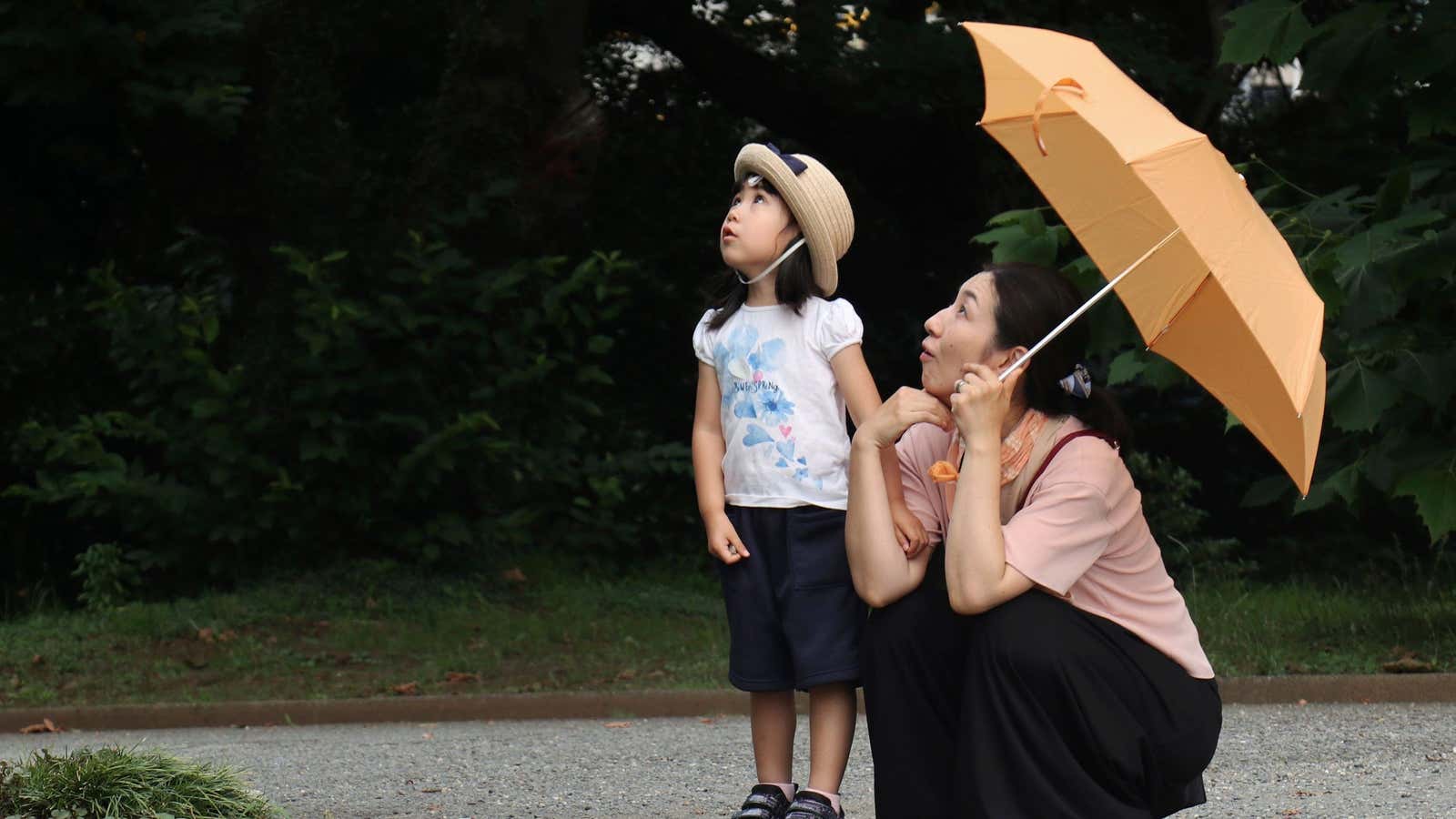 A mother and her daughter watch a butterfly at the Shinjuku Gyoen National Garden in Tokyo, Thursday, June 29, 2017.