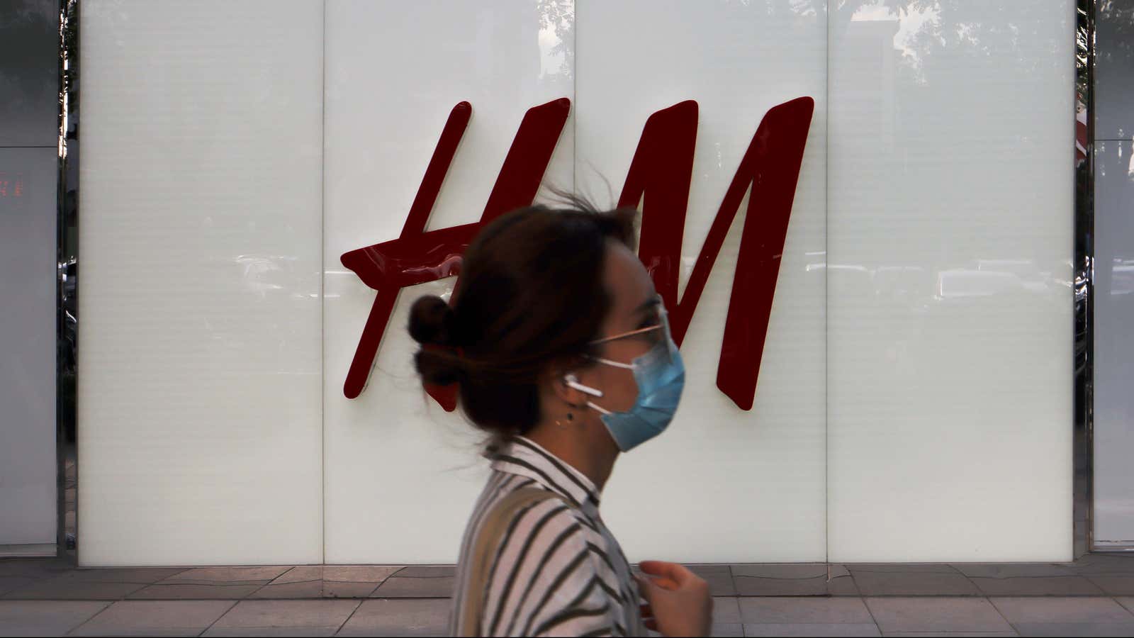 A woman walks past a store of H&amp;M.