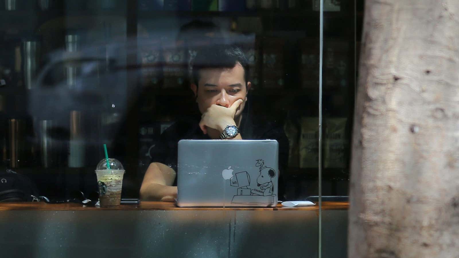 A pedestrian walks down the street while a man uses his laptop computer in a Starbucks cafe in central Sydney, Australia, October 18, 2017. REUTERS/Steven…