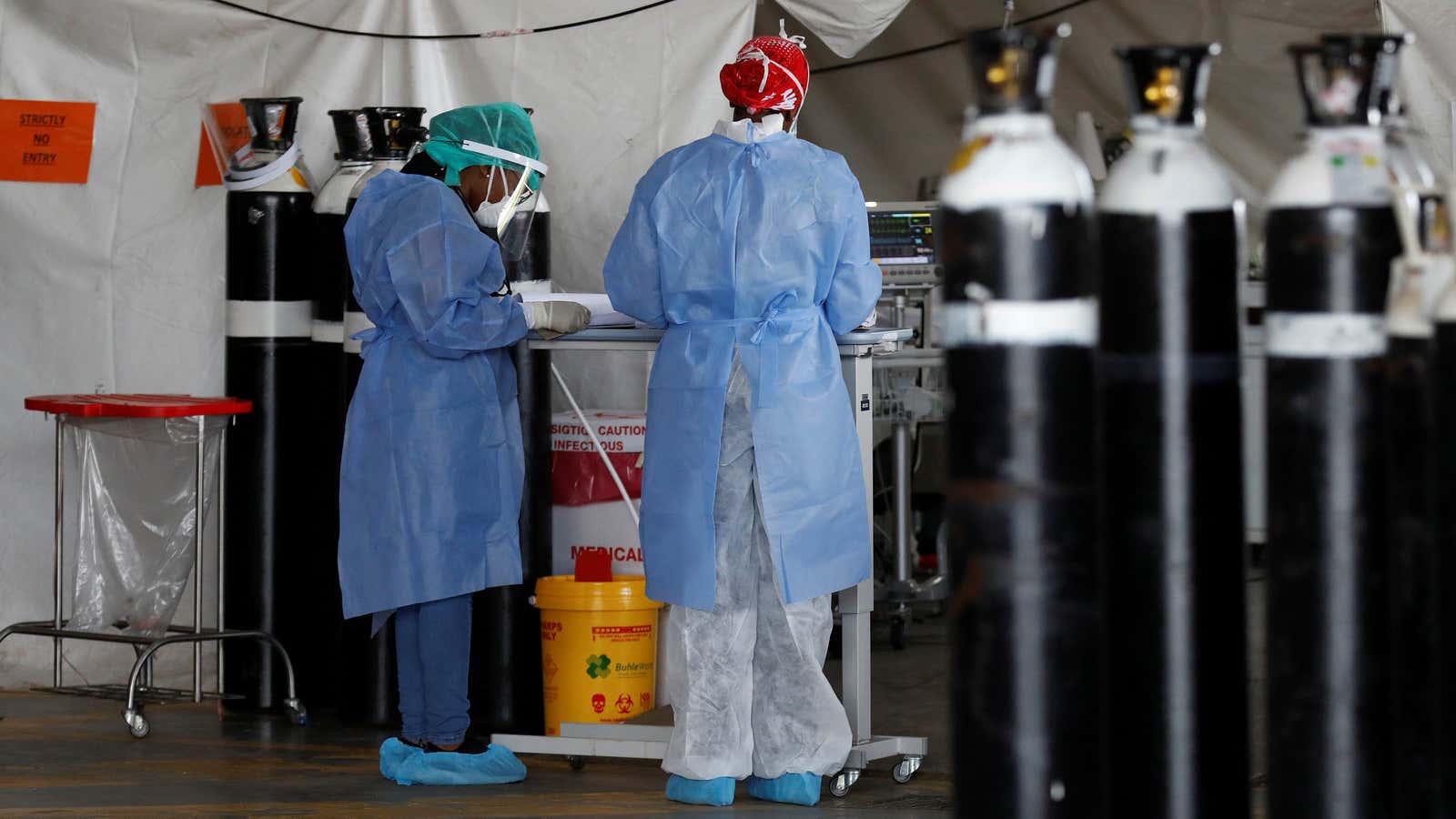 Healthcare workers stand beside empty oxygen tanks at a temporary ward set up for Covid-19 patients at Steve Biko Academic Hospital in Pretoria, South Africa, Jan. 19, 2021.