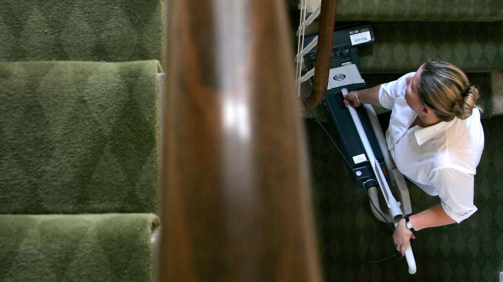 Housekeeper Belinda Sheldon vacuum cleans the stairs at Palace House at Beaulieu, the home of Lord Montagu, in southern England, October 9, 2006. REUTERS/Luke MacGregor…